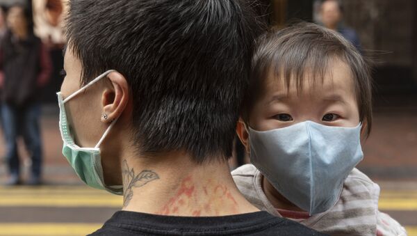 Ребенок в защитной маске на руках отца на одной из улиц в Гонконге. - Sputnik Армения
