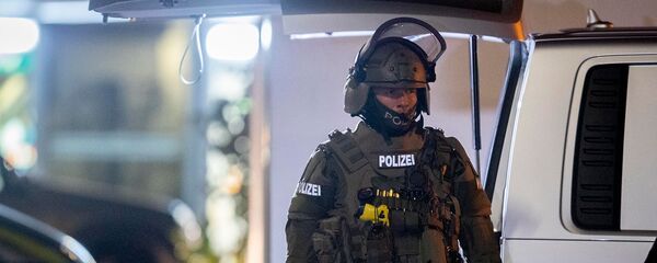 Офицер спецназа охраняет дорогу перед домом, который обыскивает полиция в Ханау после стрельбы в кальянной, где были убиты 8 человек (19 февраля 2020). Германия Офицер спецназа охраняет дорогу перед домом, который обыскивает полиция в Ханау после стрельбы в кальянной, где были убиты 8 человек (19 февраля 2020). Германия - Sputnik Армения