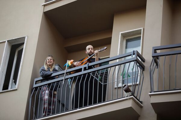 Мужчина играет на гитаре на балконе своего дома во время флешмоба, запущенного по всей Италии (13 марта 2020). Милан - Sputnik Армения