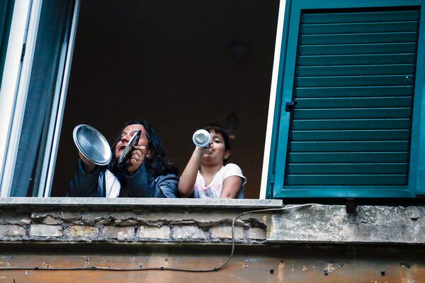 Женщина и девочка играют в горшки из окна своего дома во время флешмоба, запущенного по всей Италии, чтобы собрать людей вместе и попытаться справиться с чрезвычайной ситуацией коронавируса (13 марта 2020). Рим - Sputnik Армения