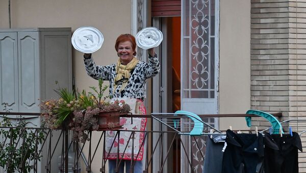 Жительница музицирует на крышках от кастрюль во время флешмоба, запущенного по всей Италии, чтобы собрать людей вместе и попытаться справиться с чрезвычайной ситуацией коронавируса (13 марта 2020). Рим - Sputnik Армения