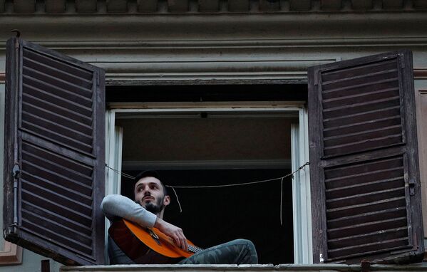 Мужчина играет на гитаре, сидя на подоконнике, во время флешмоба, запущенного по всей Италии (13 марта 2020). Рим - Sputnik Армения