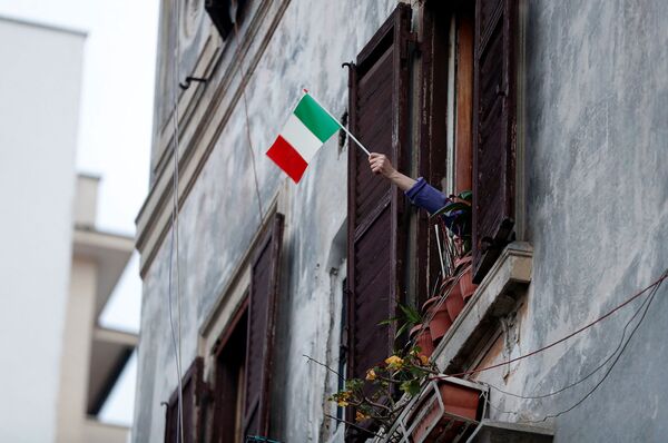 Житель размахивает флагом Италии из окна дома во время флешмоба, запущенного по всей Италии (13 марта 2020). Рим - Sputnik Армения