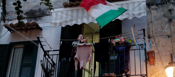 Жительница с флагом Италии из окна во время флешмоба, запущенного по всей Италии, чтобы собрать людей вместе и попытаться справиться с чрезвычайной ситуацией коронавируса (13 марта 2020). Неаполь - Sputnik Армения