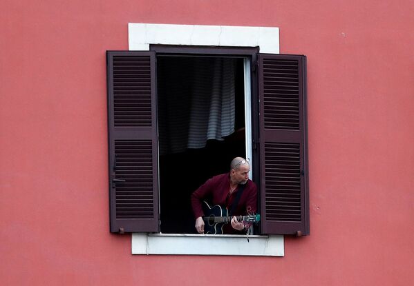 Мужчина играет на гитаре из окна своей квартиры во время флешмоба, запущенного по всей Италии (13 марта 2020). Рим - Sputnik Армения