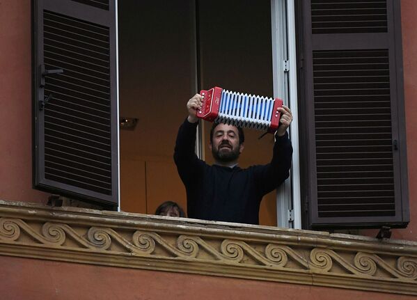 Мужчина играет на аккордеоне из окна своей квартиры во время флешмоба, запущенного по всей Италии (13 марта 2020). Рим - Sputnik Армения
