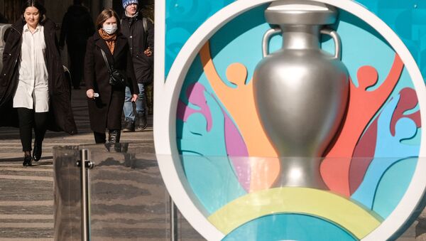 Женщина в защитной маске проходит мимо часов, отсчитывающих дни до Евро-2020 УЕФА на Большой Морской улице (17 марта 2020). Санкт-Петербург - Sputnik Армения