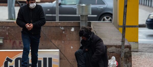 Молодой человек в защитной маске проходит мимо бездомной женщины - Sputnik Արմենիա