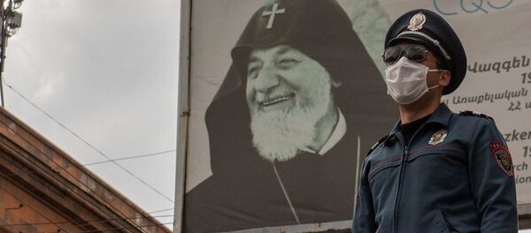Полицейский в защитной маске на фоне баннера во время чрезвычайной ситуации (25 марта 2020). Ереван - Sputnik Արմենիա