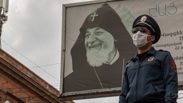 Полицейский в защитной маске на фоне баннера во время чрезвычайной ситуации (25 марта 2020). Ереван - Sputnik Армения