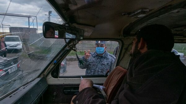 Полицейский проверяет документы у водителей и пассажиров автомобилей, выезжающего из столицы (2 апреля 2020). Еревaн - Sputnik Армения