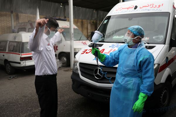 Член экстренного медицинского персонала проходит дезинфекцию после перевода пациента с коронавирусной болезнью (30 марта 2020). Тегеран - Sputnik Армения
