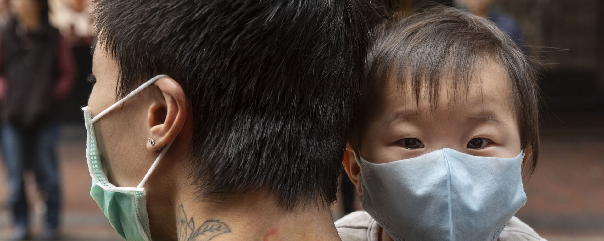 Ребенок в защитной маске на руках отца на одной из улиц в Гонконге - Sputnik Արմենիա, 1920, 25.05.2020