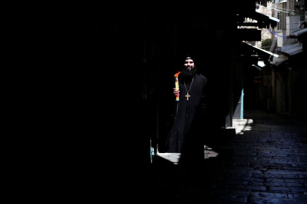  Православный христианский священнослужитель держит свечи в руках после церемонии сошествия Благодатного Огня (18 апреля 2020). Иерусалим - Sputnik Армения