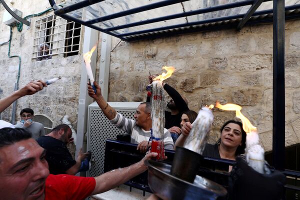 Православные верующие держат в руках подсвечники с огнем, который они раздают жителям Старого Города (18 апреля 2020). Иерусалим - Sputnik Армения