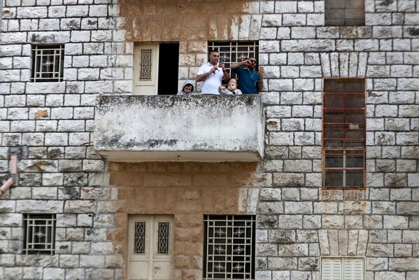 Палестинцы наблюдают со своего балкона за церемонией Благодатного Огня (18 апреля 2020). Иерусалим - Sputnik Армения