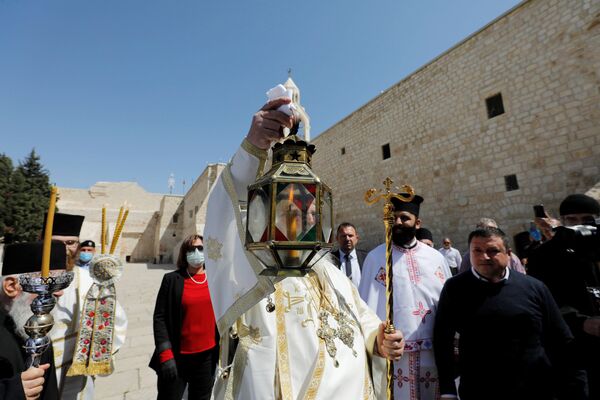 Глава греческой православной церкви в Вифлееме епископ Феофилактос держит свечу, зажженную от Благодатного Огня (18 апреля 2020). Иерусалим - Sputnik Армения