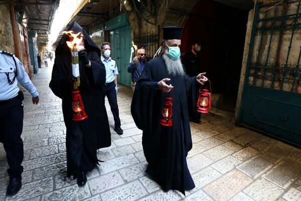 Православные священнослужители держат в руках свечу и лампы во время церемонии сошествия Благодатного огня (18 апреля 2020). Иерусалим - Sputnik Армения