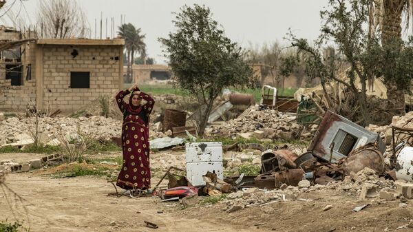 Женщина в платке рядом с останками разрушенного дома в восточной сирийской деревне Багхуз в провинции Дейр-эз-Зор (13 марта 2020). - Sputnik Արմենիա