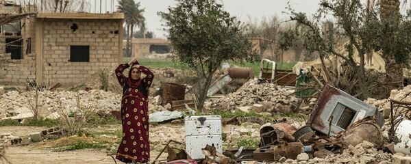 Женщина в платке рядом с останками разрушенного дома в восточной сирийской деревне Багхуз в провинции Дейр-эз-Зор (13 марта 2020). - Sputnik Армения