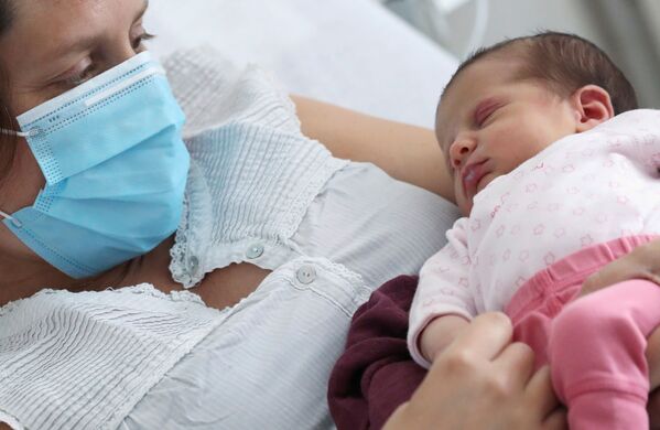 Зараженная коронавирусом женщина в защитной маске с новорожденной дочерью в больнице Брюсселя, Бельгия - Sputnik Армения