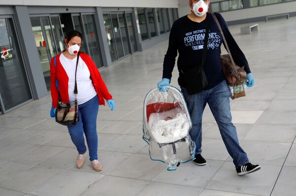 Супруги в защитных масках и с новорожденным сыном покидают больницу в городе Ронда, Испания - Sputnik Армения