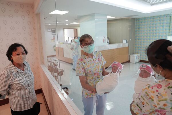 Медсестры в защитных лицевых масках держат новорожденных в защитных лицевых щитках в целях профилактики коронавируса в больнице в Бангкоке, Таиланд - Sputnik Армения