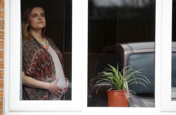 Беременная девушка в окне своей гостинной в Манчестере, Великобритания - Sputnik Армения