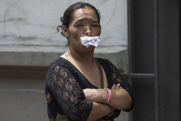 Женщина держит бумагу во рту, как альтернативу маске, в очереди за бесплатным обедом для бездомных в Лиме, ​​Перу - Sputnik Армения