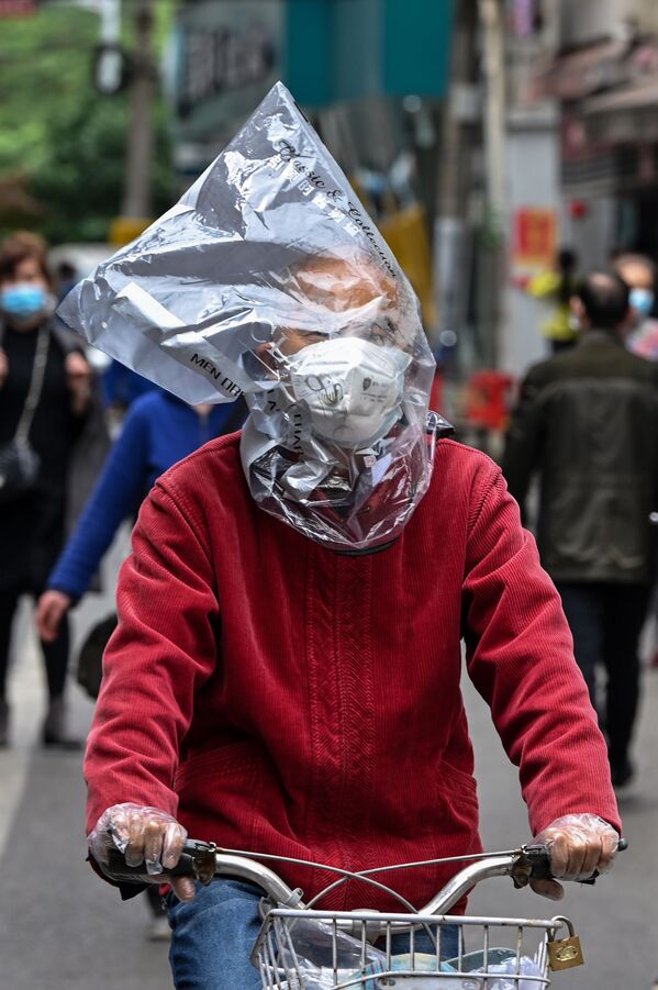Велосипедист в защитной маске и с пластиковым пакетом на голове на одной из улиц Уханя, Китай - Sputnik Армения