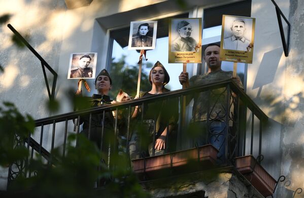 Жители дома с портретами родственников-фронтовиков поют песни на балконе в рамках всероссийской акции #ПоемДеньПобеды в Севастополе - Sputnik Армения