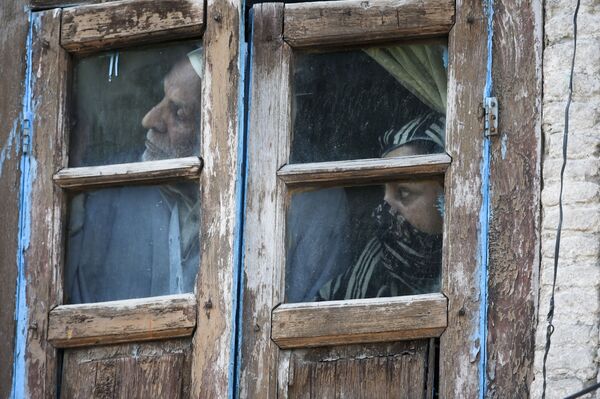 Люди смотрят из окна своего дома в Сринагаре, Индия - Sputnik Армения