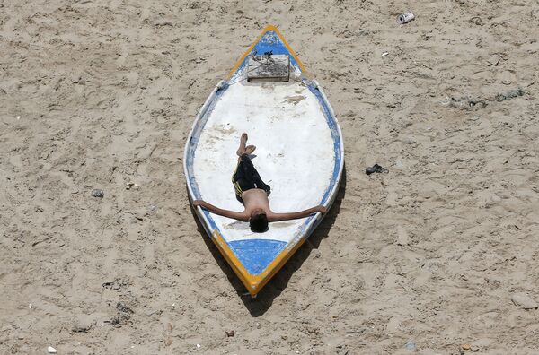 Палестинский юноша во время отдыха на пляже в Газе  - Sputnik Армения