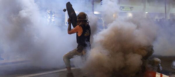 Протестующий прикрывается скейтбордом от слезоточивого газа во время демонстрации в связи со смертью Джорджа Флойда, убитого полицейским (29 мая 2020). Миннеаполис - Sputnik Армения