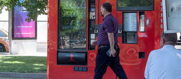 Мужчина в маске проходит мимо торгового аппарата в Ереване Мужчина в маске проходит мимо торгового аппарата в Ереване - Sputnik Армения