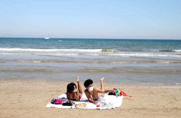 Девушки в защитных медицинских масках на пляже Malvarrosa в Валенсии, Испания - Sputnik Армения