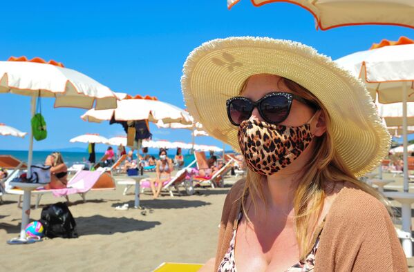 Женщина в защитной маске и солнцезащитных очках на пляже в Кастильоне-делла-Пеская, Италия - Sputnik Армения