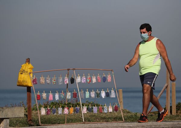 Պաշտպանիչ դիմակով տղամարդն անցնում է վաճառքի համար ցուցադրված դիմակների կողքով, Ռիո դե Ժանեյրո, Բրազիլիա։ - Sputnik Արմենիա