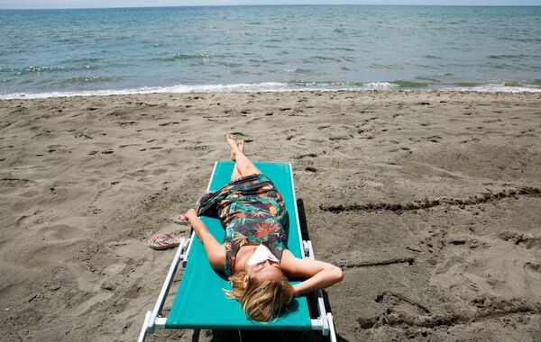 Девушка загорает на пляже в Италии - Sputnik Армения
