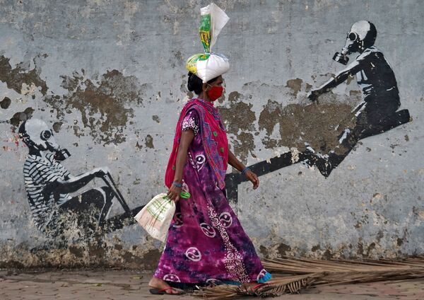 Женщина в защитной маске проходит мимо граффити в Мумбаи - Sputnik Армения