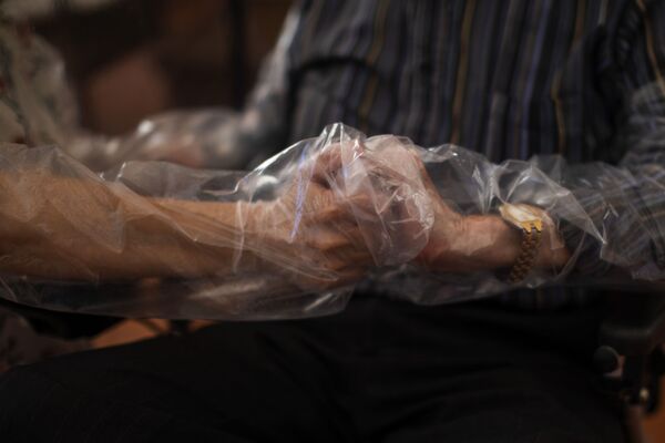 61-летняя Долорес Рейес Фернандес держит за руки своего отца Хосе Рейеса Лозано, впервые за 4 месяца, в доме престарелых в Барселоне, Испания - Sputnik Армения