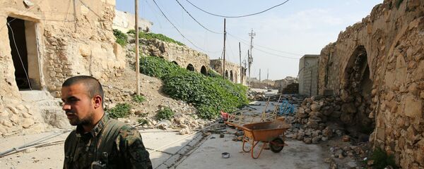 Боец езидов из базирующихся в Сирии Народных подразделений защиты, более известных как YPG, идет по разрушенным улицам Синджара (29 января 2015). Ирак - Sputnik Армения