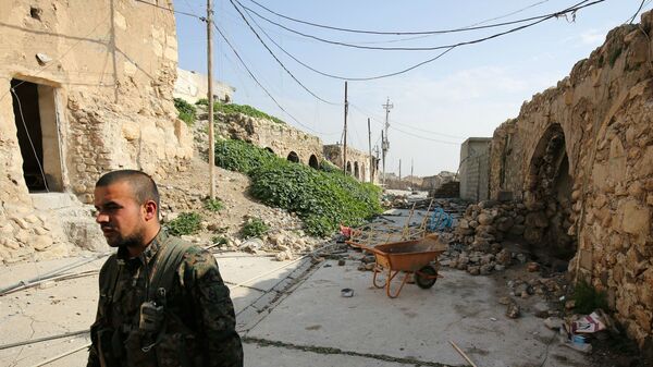 Боец езидов из базирующихся в Сирии Народных подразделений защиты, более известных как YPG, идет по разрушенным улицам Синджара (29 января 2015). Ирак - Sputnik Армения