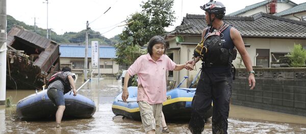 Спасатель помогает женщине во время эвакуации в японской префектуре Кумамото - Sputnik Армения