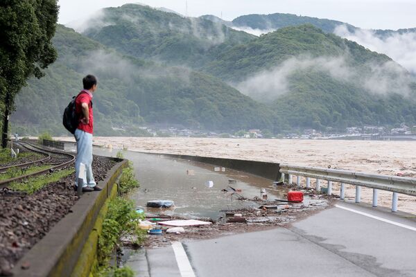 Мужчина у разрушенной дороги вследствие сильных дождей в японской префектуре Кумамото - Sputnik Армения