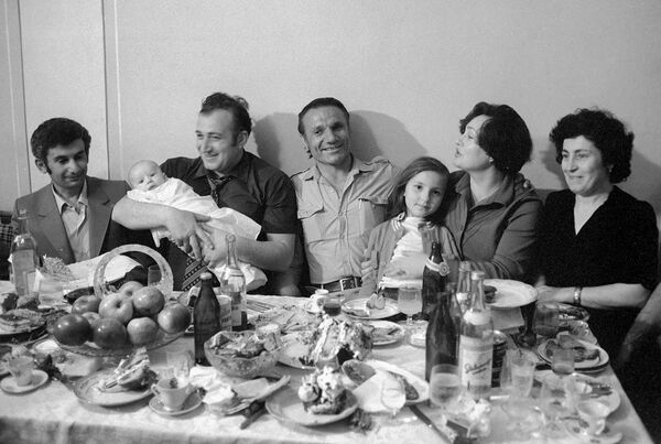 Шаварш Владимирович Карапетян (второй слева), спасший из свалившегося в результате аварии в Ереванское озеро троллейбуса 20 человек, с новорожденным сыном хозяев дома Гусевых на руках - Sputnik Армения