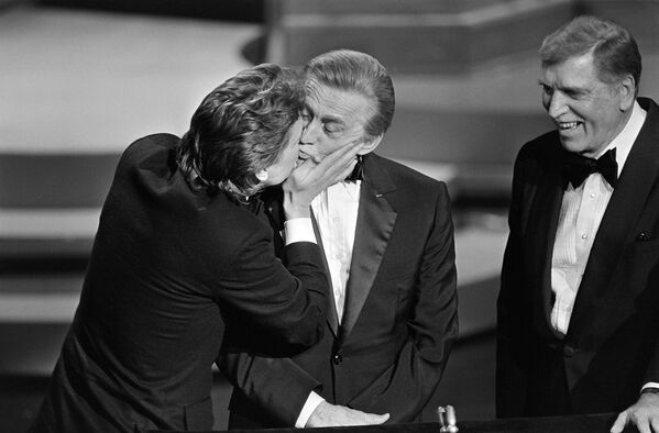 Сын Майкл Дуглас целует отца Кирка Дугласа во время Оскара, 1985 год - Sputnik Армения