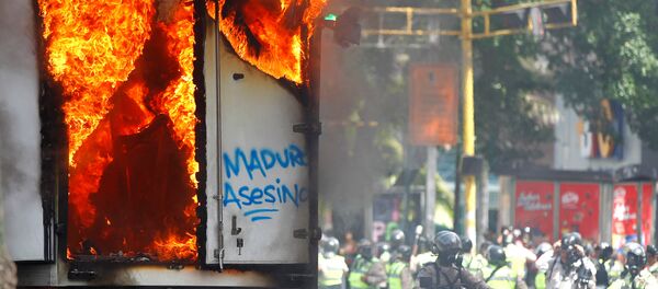 Сотрудники сил безопасности собираются рядом с правительственным грузовиком, который был подожжен во время митинга против правительства президента Венесуэлы Николаса Мадуро в Каракасе, Венесуэла - Sputnik Армения