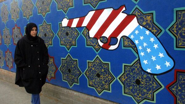 Женщина проходит мимо бывшего здания посольства США в Иране, на стене которого нарисован револьвер цветами американского флага - Sputnik Արմենիա