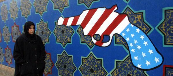 Женщина проходит мимо бывшего здания посольства США в Иране, на стене которого нарисован револьвер цветами американского флага - Sputnik Армения